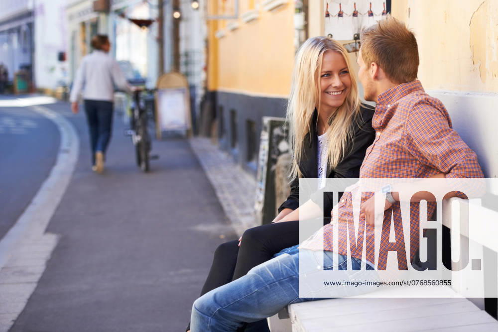 Couple, love or happy on bench in city, weekend relax or communication in healthy relationship. English man, woman or smile for conversation in marriage, care or romance together outdoor in cambridge. model released property released