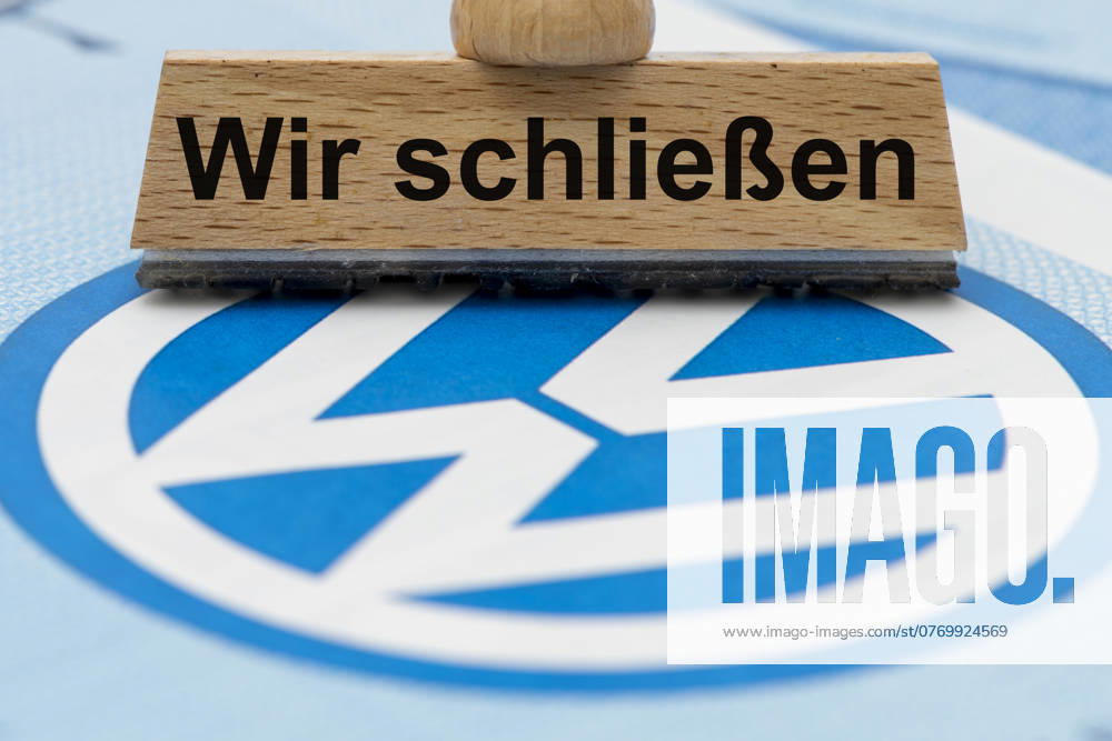 VW crisis with risk of plant closure A wooden stamp is labeled with the words We are closing, above a VW share with logo Symbolic image