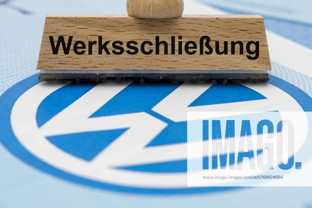 VW crisis with risk of plant closure A wooden stamp is labeled with the words plant closure, above a VW share with logo symbol image