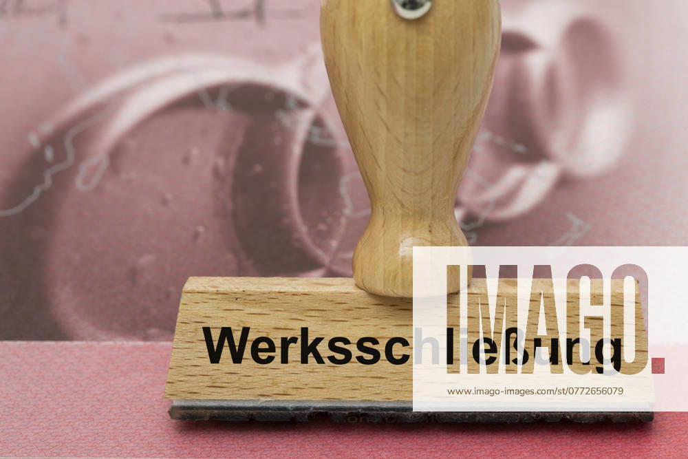 AUDI crisis with risk of plant closure A wooden stamp is labeled with the words plant closure, above an AUDI share Symbolic image