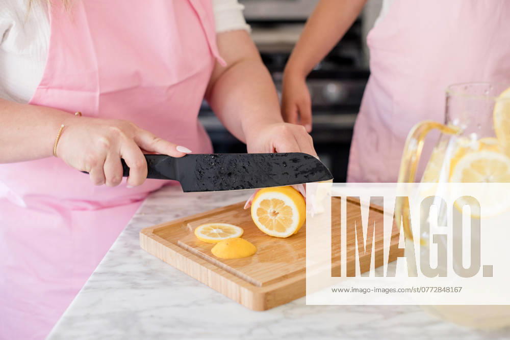 Mother slicing lemons on a cutting board in the kitchen for lemonade San Francisco, California, United States CR_HOOX240731-1501870-01 ,model released, Symbolfoto ,property released