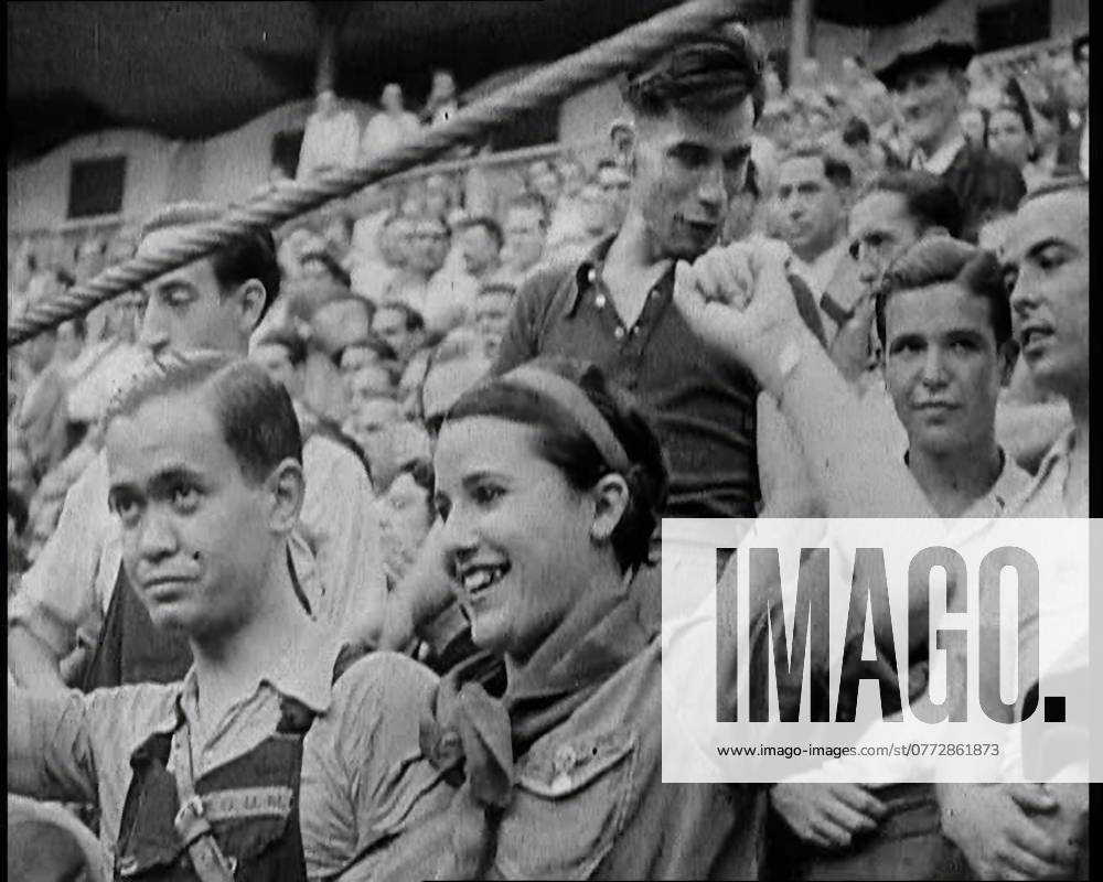 Spectators at Bullring Cheering Parading Government Fighters, Including Woman With Raised Left Fist, 1937. Spanish Civil War. Spain s ...bullrings full of men and women lusting not for the blood of toros, but of the enemy . From Time To Remember - Sense Of Values, 1937 (Reel 2); documentary film about the events of 1937, war in the Far East, build up to war in Europe.