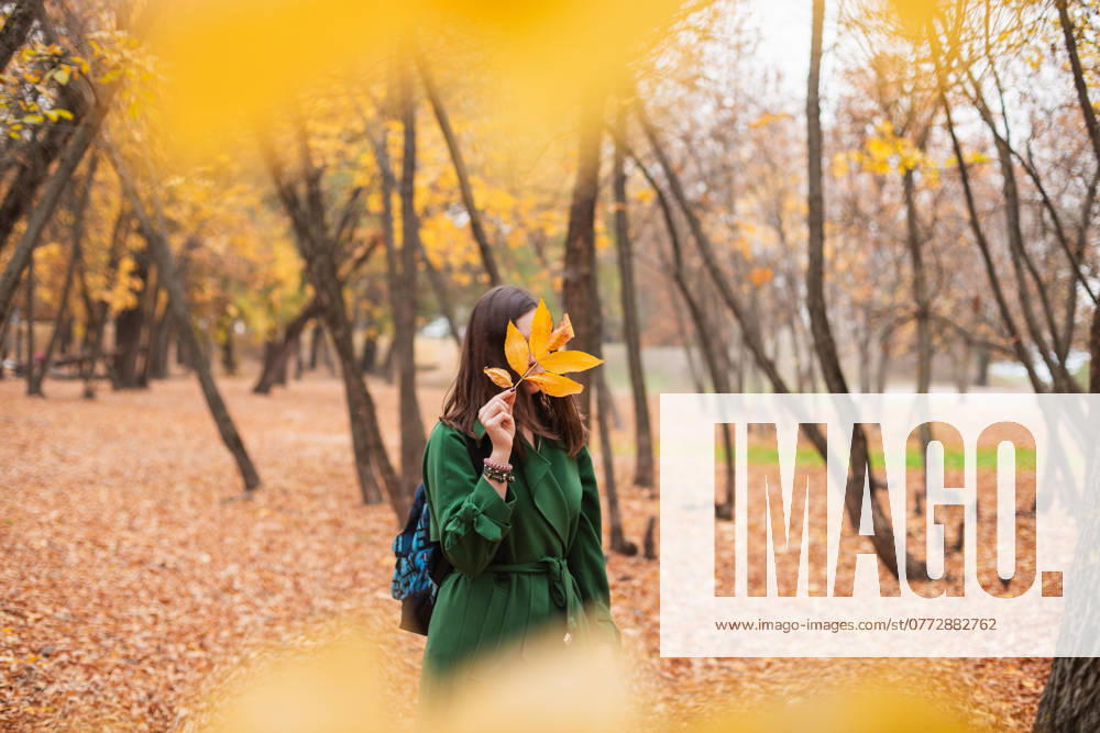Front view of a young woman with a yellow leaf in front of her face Tallinn, Harju County, Estonia R_GHEW2410140E-1562931-01 ,model released, Symbolfoto