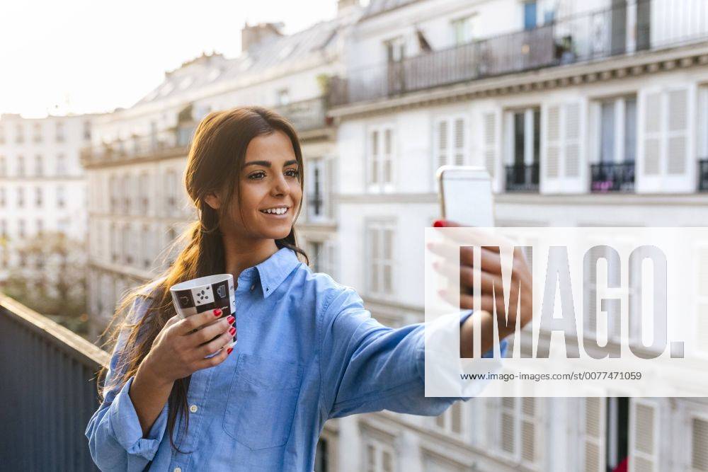 Young woman standing on balcony takinf smart phone selfie model released Symbolfoto MGOF02869