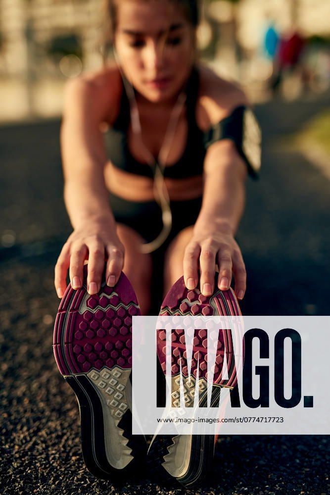 Girl, runner and stretching legs on ground, outdoor and warm up for exercise or fitness training. Female person, earphones and athlete for cardio preparation, muscle flexibility and music for workout. model released property released