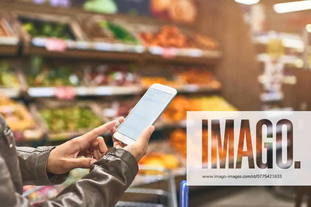 Person, hands and shopping list at grocery store on smartphone in shelf for food and product. Customer, aisle and supermarket or convenience shop for retail cost, prices and discount or promotion. model released property released