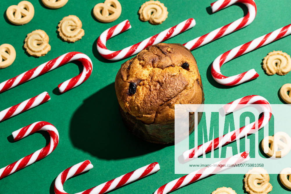 Delicious Christmas sweets including a panettone, candy canes, and butter cookies arranged artistically on a vibrant green background, adding a festive look to seasonal celebrations. Model Released AlexSalcedo_ID24525_711107_024