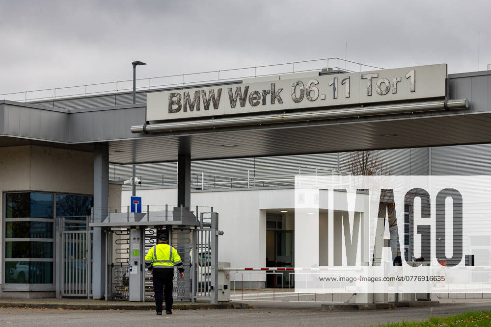Automotive industry Entrance gate 1 of the BMW plant in Regensburg An employee in a yellow high-visibility vest enters the plant premises through a turnstile The modern building shows the company sign BMW Plant 06 11 Gate 1 on a gray background Regensburg Burgweinting Harting Bavaria Germany 20241030-286A3343-M4000