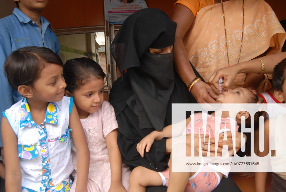 A Muslim woman holds her child in her hands to administer Polio vaccination during Pulse Polio drive in Bombay now Mumbai, Maharashtra, India