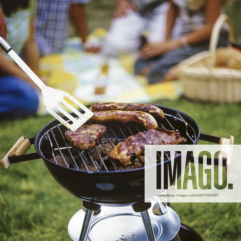 Steaks und Bratwuerste auf Grill, Leute im Hintergrund (model-released)