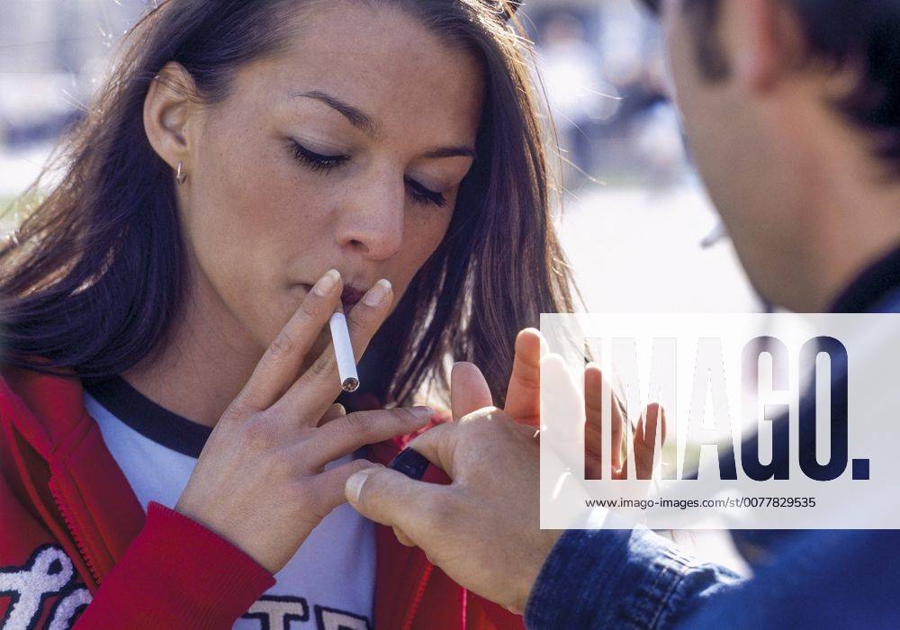 Mann gibt junger Frau Feuer fuer Zigarette (model-released)