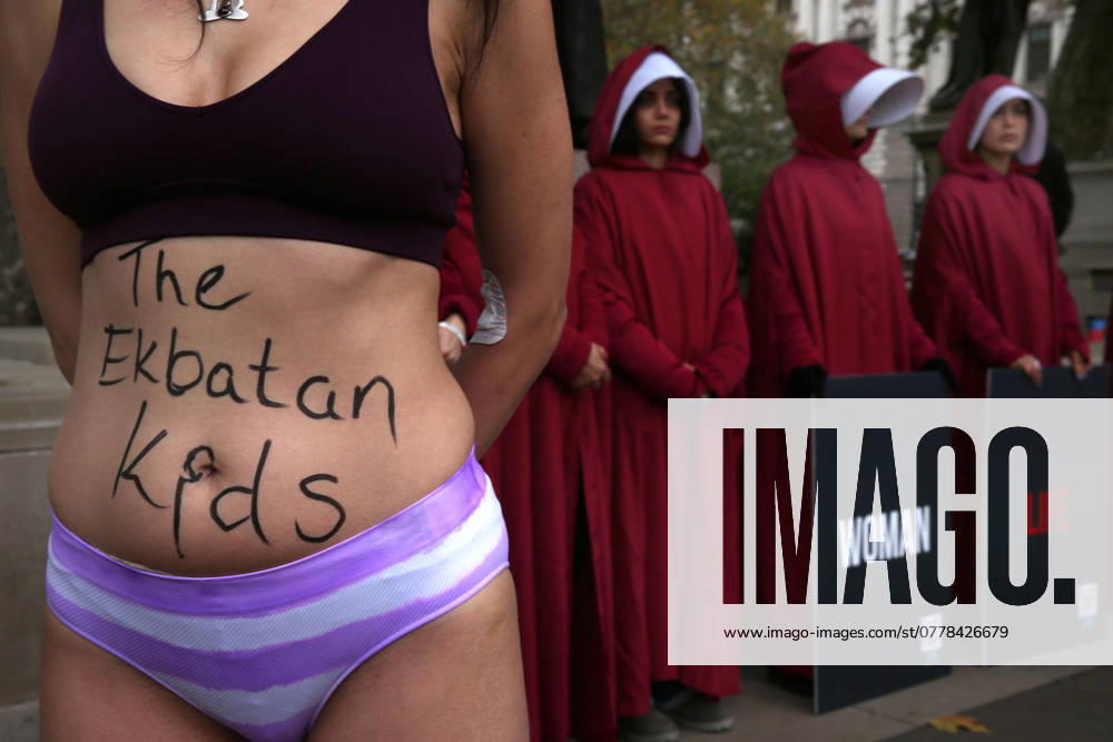 A protester recreates the actions of AHOO DARYAEI with ‘The Ekbatan kidsâ€⠢ written on her stomach as she and protesters dressed in Housemaidâ€⠢s Tale costumes meet in Parliament Square. Protesters wear costumes inspired by the Handmaidâ€⠢s Tale that are recognised as a symbol of female oppression faced by women of Iran. The protesters are also highlighting the plight of AHOO DARYAEI who stripped down to her underwear after being harassed by paramilitary forces for not wearing the hijab correctly on November 02 2024 she remains detained. This action has turned her into symbol of resistance against Iranâ€⠢s strict dress code laws. London UK - ZUMAmp3_ 20241108_zip_mp3_022