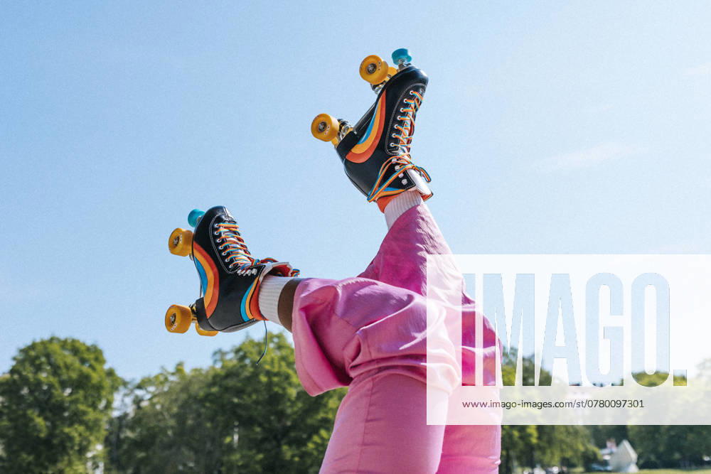 Low section of woman wearing rainbow striped roller skates under blue sky Sweden, Stockholm, model released