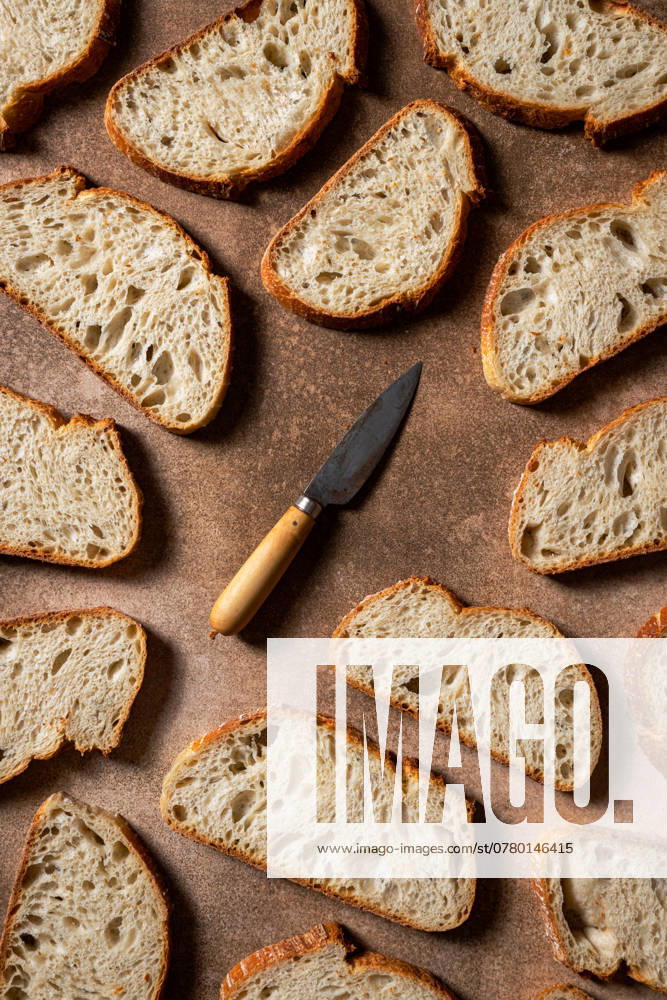 A composition featuring artisan bread slices arranged on a rustic surface, showcasing a mix of textures A vintage knife adds character to the scene, enhancing the artisanal theme Model Released CintiaViudez_ID24986_723837_003