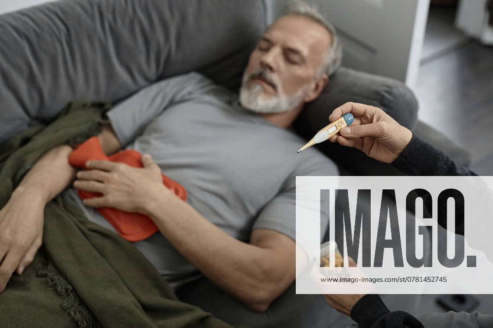 Unrecognizable woman looking at thermometer while sitting next to sick husband at home model released, Symbolfoto, KPEF00367