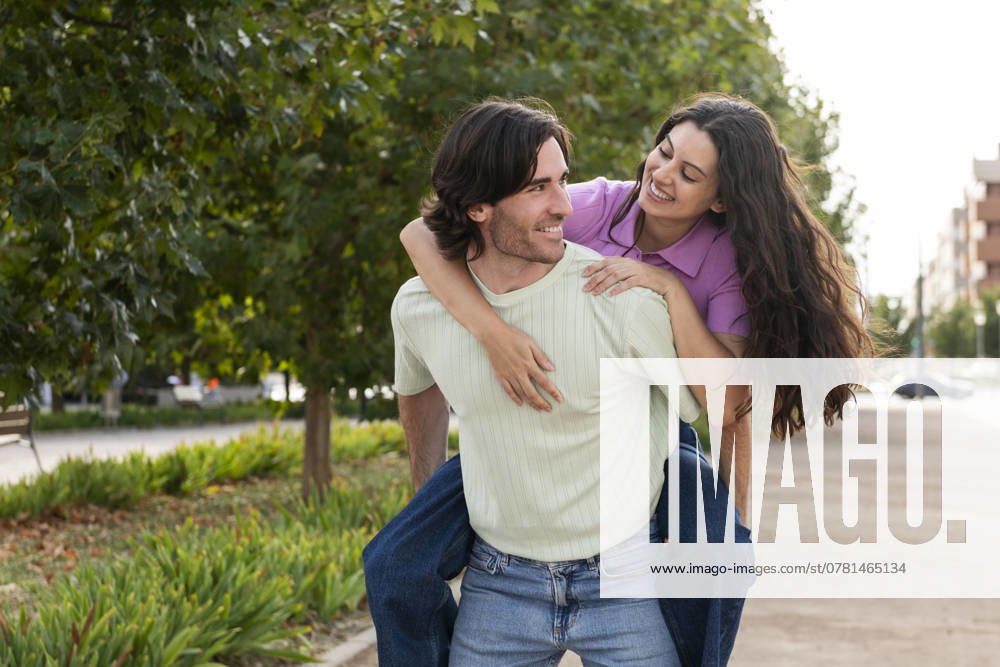 Young man piggybacking woman and walking in park model released, Symbolfoto, LMCF01839