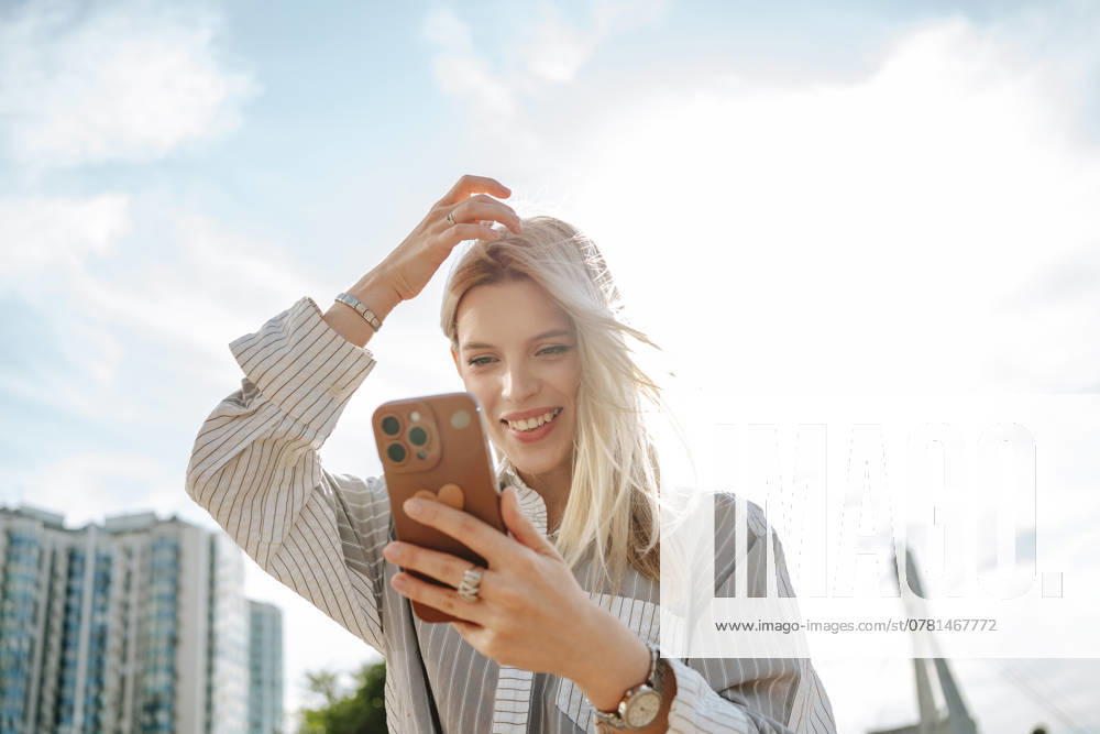 Blond young woman with hand in hair using mobile phone model released, Symbolfoto, MDOF02698