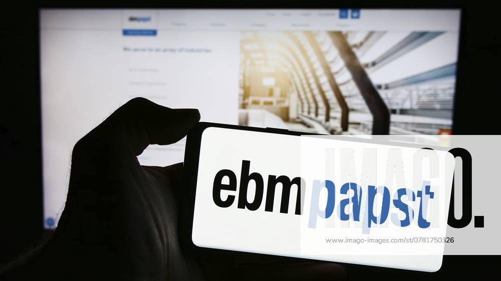 Stuttgart, Deutschland, 13.04.2024: Eine Person hält ein Mobiltelefon mit dem Logo des deutschen Elektromotorenherstellers EBM Papst Gruppe vor einer Unternehmenswebseite. Fokus auf das Telefondisplay, Europa Stuttgart, Germany, 04-13-2024: Person holding mobile phone with logo of German electric motor company EBM-Papst Gruppe in front of business web page. Focus on phone display, Europe