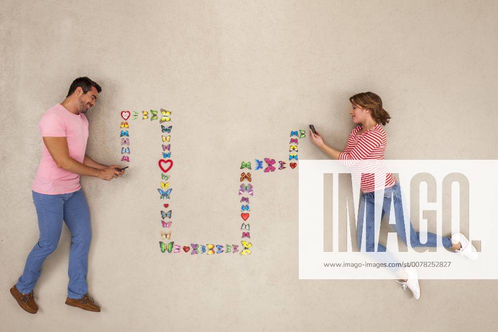 Man and woman sending love messages from smart phone model released Symbolfoto BAEF01304