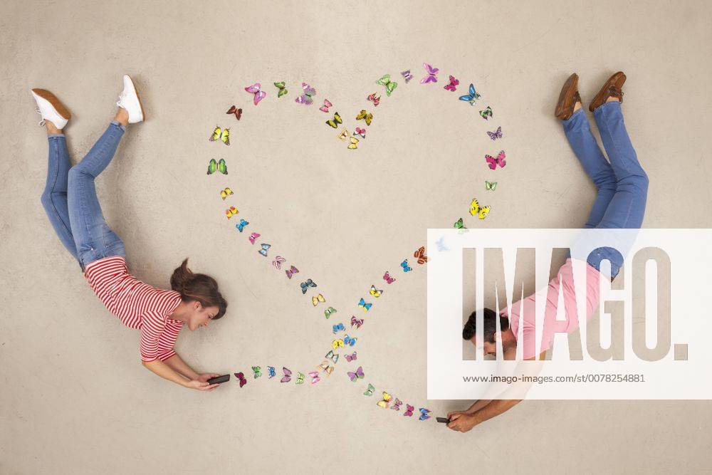 Man and woman sending love messages from smart phone model released Symbolfoto BAEF01308