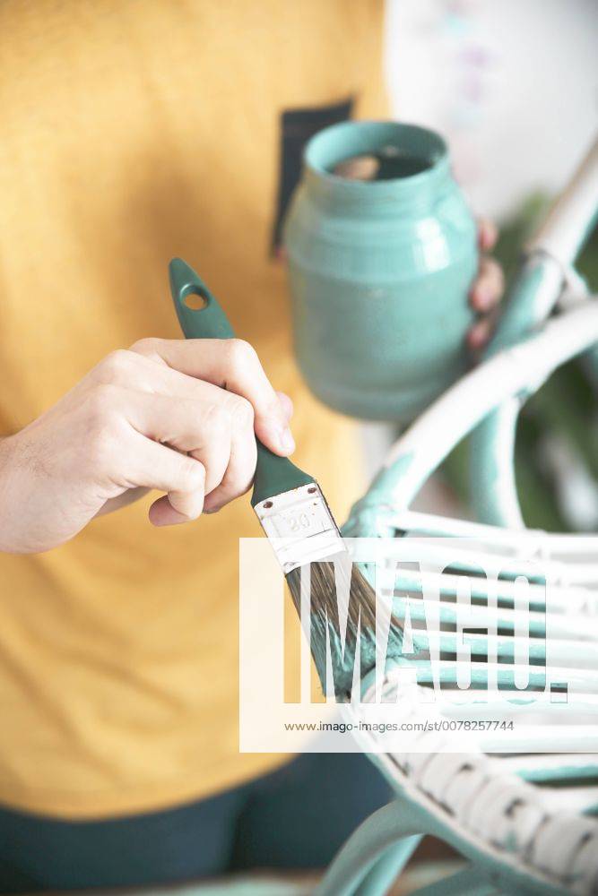 Close-up of man painting wicker armchair model released Symbolfoto property released RTBF00769