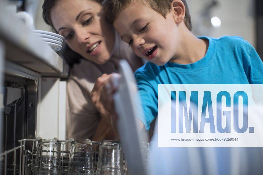 Boy packing plates into dishwasher model released Symbolfoto property released ZEF13316