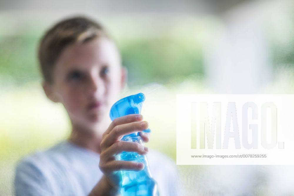 Boy spraying with window cleaner model released Symbolfoto property released ZEF13465