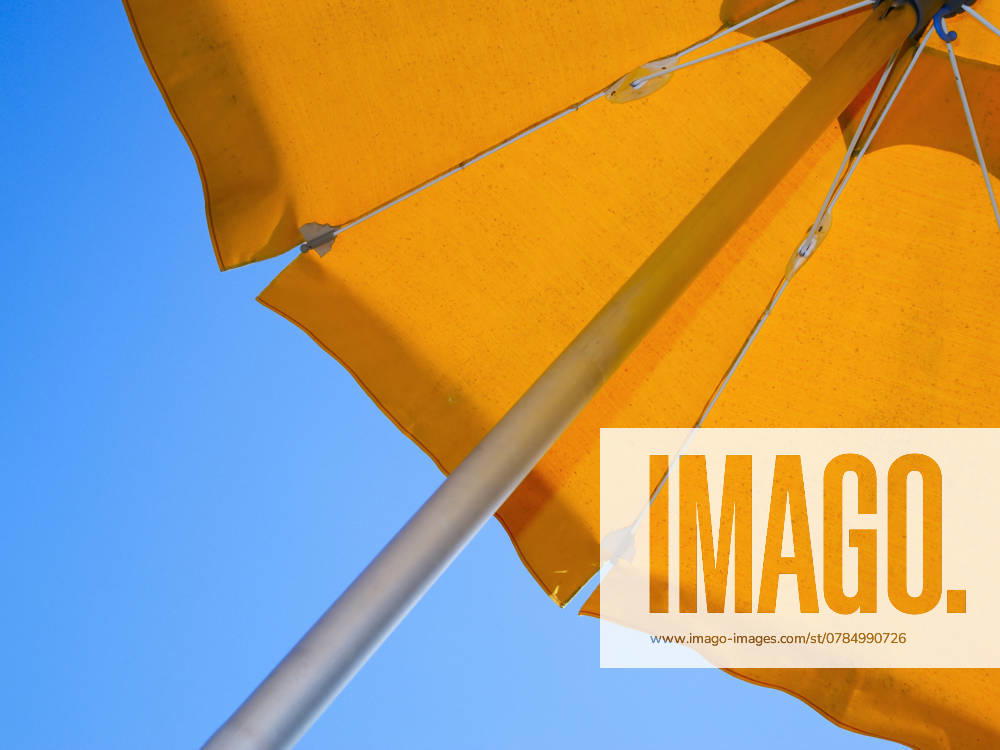 Sunshade slanting Teilansicht eines orange-farbenen Sonnenschirms von unten in Schrägansicht vor blauen Himmel ,model released, Symbolfoto