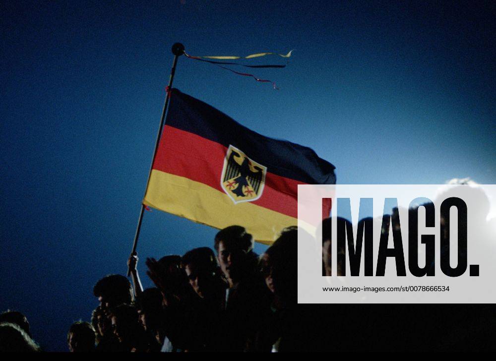 Menschen waehrend der Deutschen Wiedervereinigung mit einer Deutschen Flagge. Berlin den 03.10.1990, Â Berlin Deutschland