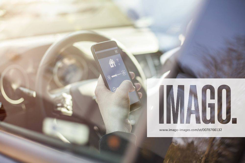 Man in car adjusting devices at home via smartphone model released Symbolfoto property released NAF00086