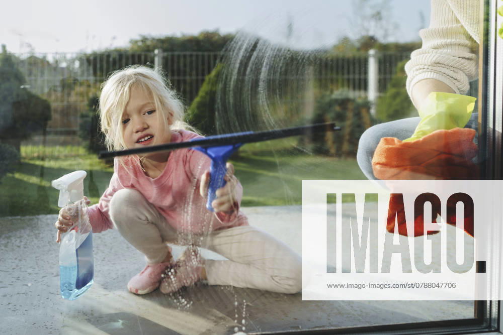 Little girl cleaning glass window with father at home model released, Symbolfoto property released, NSTF00378