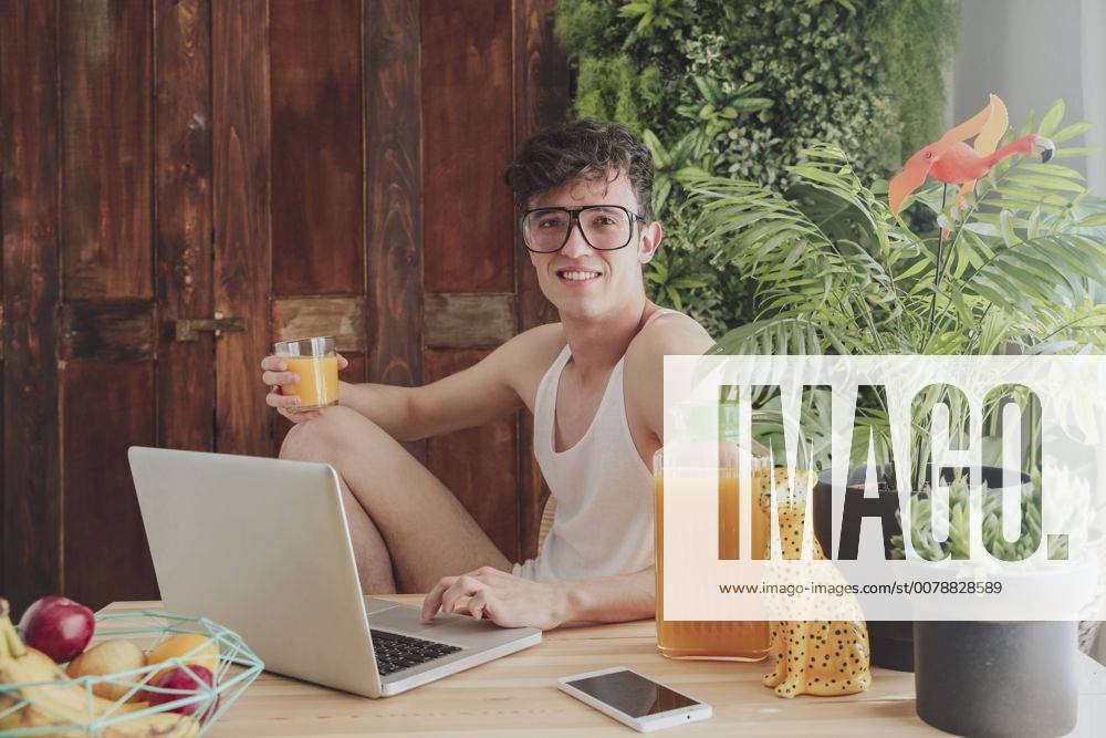 Young man using laptop and drinking orange juice at home model released Symbolfoto RTBF00826