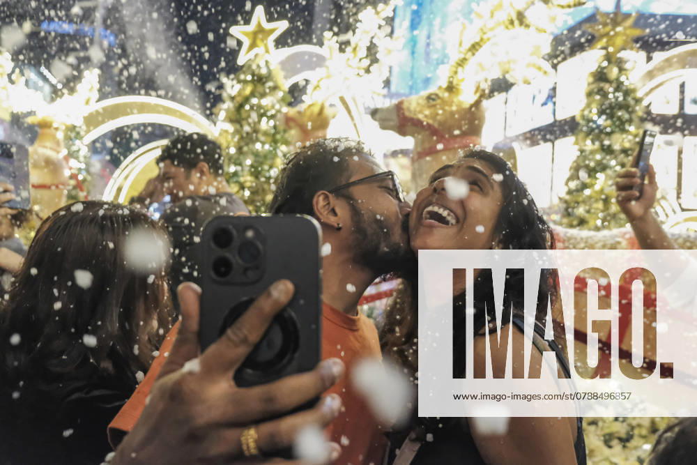 A man kisses his spouse as the artificial snow falls during the Christmas eve celebration at Bukit Bintang. Kuala Lumpur Malaysia - ZUMAs197 20241224_aaa_s197_189