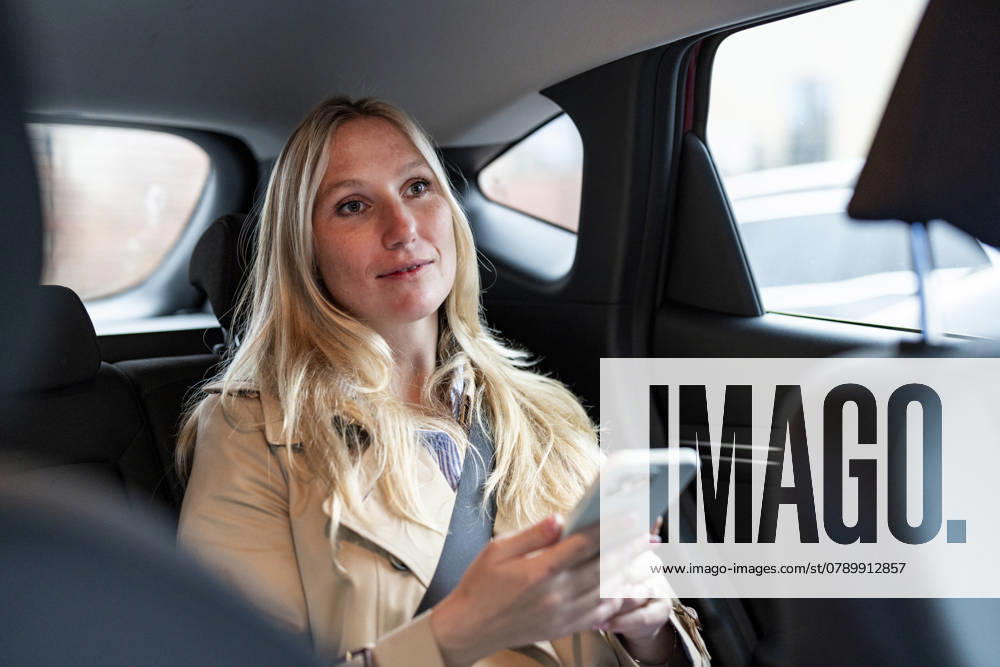 Businesswoman with smart phone sitting at back seat of car model released, Symbolfoto, WPEF09624