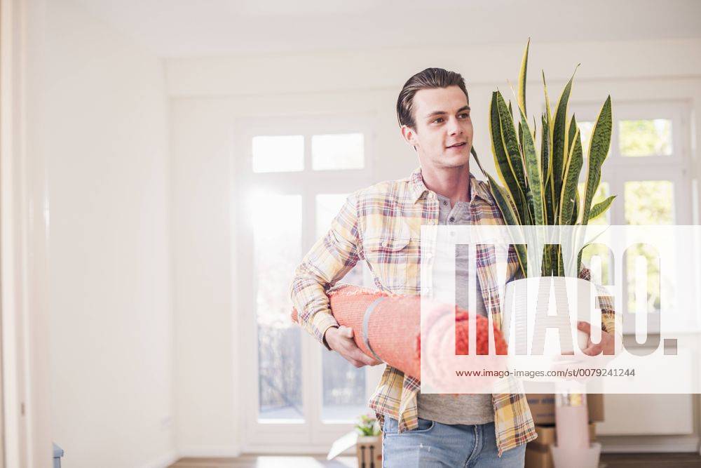 Young man carrying belongings in new home model released Symbolfoto property released UUF10756