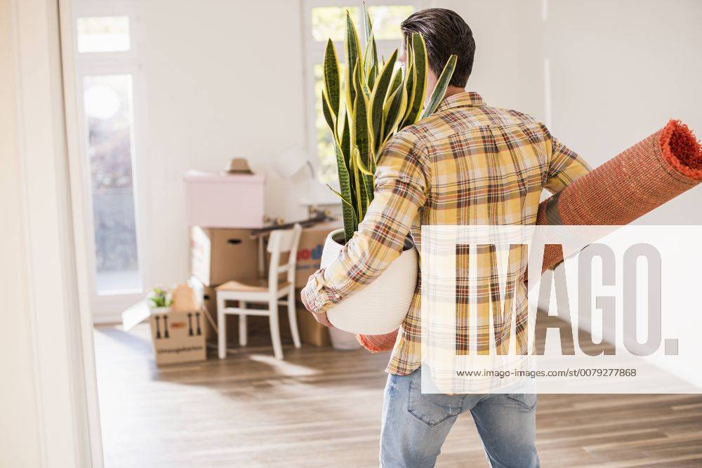 Young man carrying belongings in new home model released Symbolfoto property released UUF10757