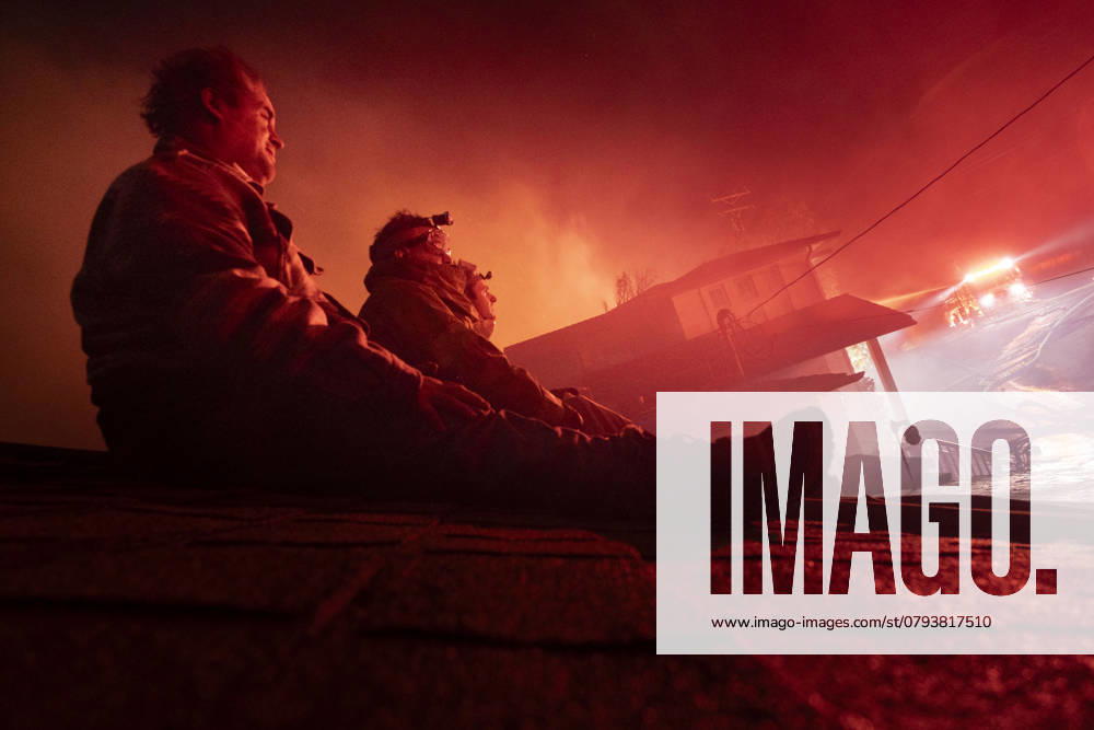 Homeowners who stayed behind to defend their house from the Paradise fire sit on their roof, watching as firefighters battle a fire inside of a home along the Pacific Coast Highway in Malibu, CA. California United States - ZUMAs197 20250108_aaa_s197_531