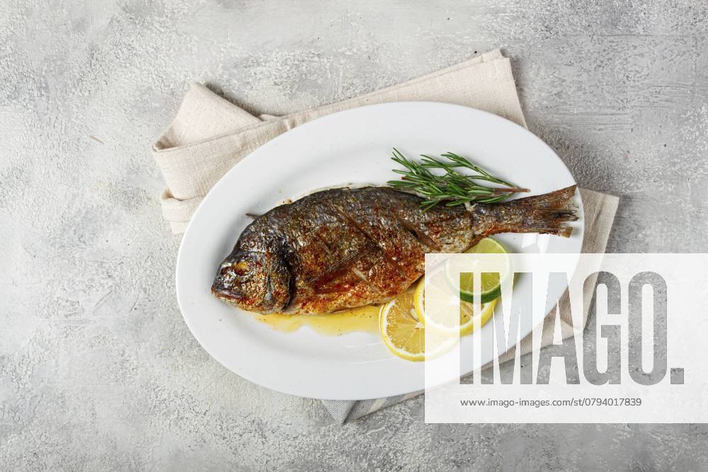 Gebackene Goldbrasse, im Ofen, gebratene Goldbrasse, mit Gewürzen und Kräutern, auf einem weißen Teller, von oben, hausgemacht, ohne Personen Baked dorado fish, in the oven, fried dorado, with spices and herbs, on a white plate, top view, homemade, no people