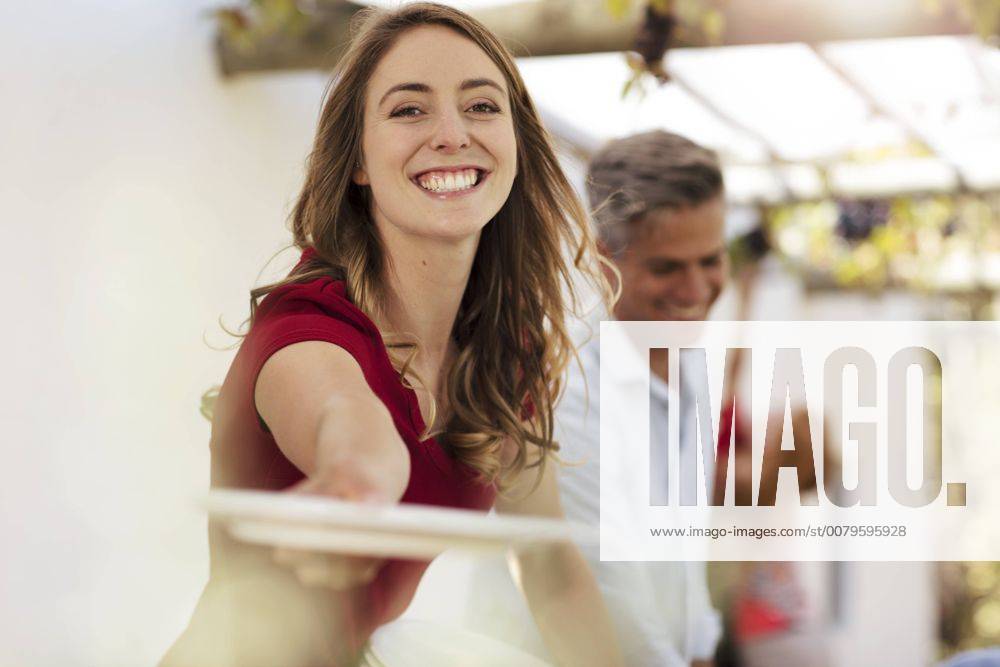 Smiling woman handing over plate on agarden party model released Symbolfoto property released ZEF13961