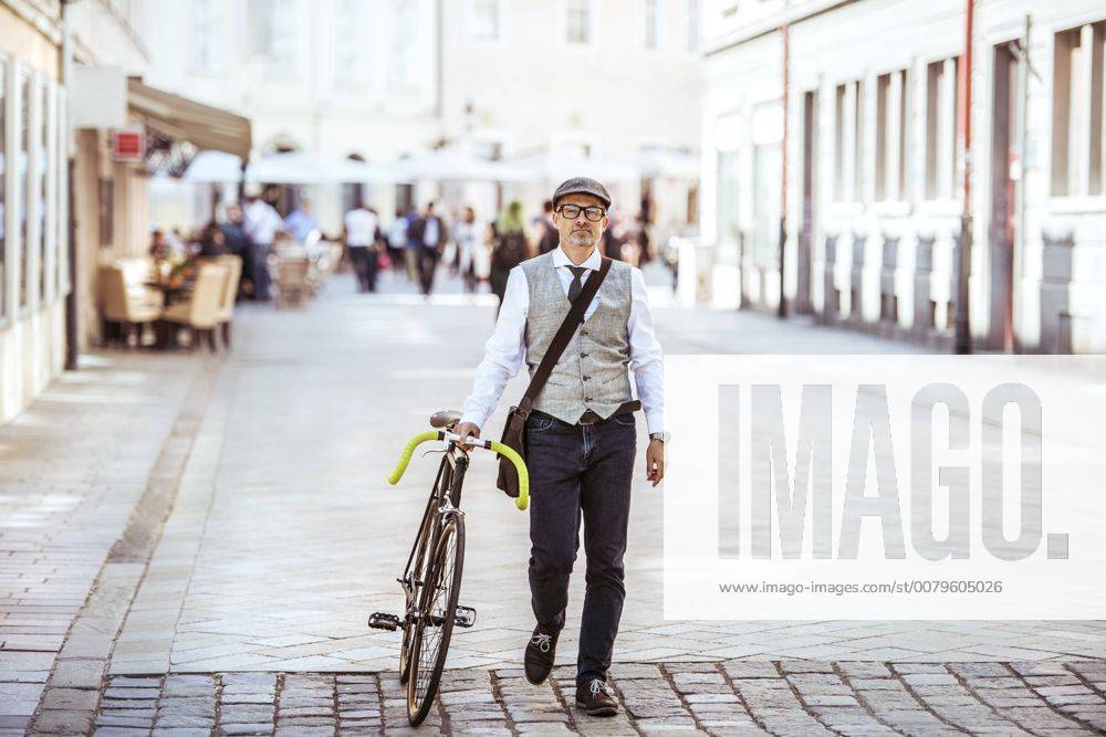 Mature businessman pushing bicycle in the city model released Symbolfoto HAPF01781