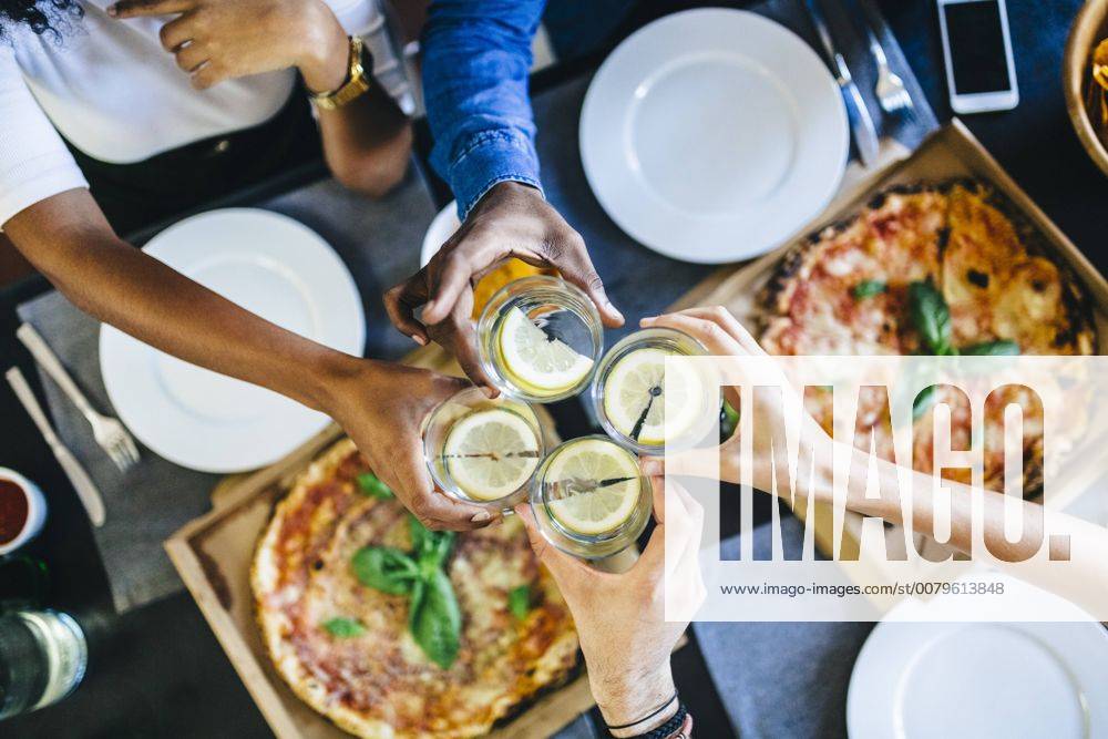 Group of friends having pizza and clinking glasses of water at home model released Symbolfoto GIOF02740