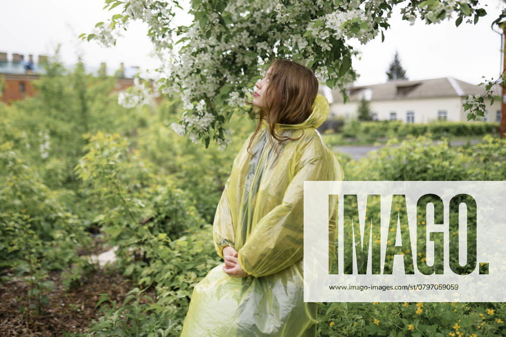 Young woman wearing raincoat at back yard of house model released, Symbolfoto, VCF00549