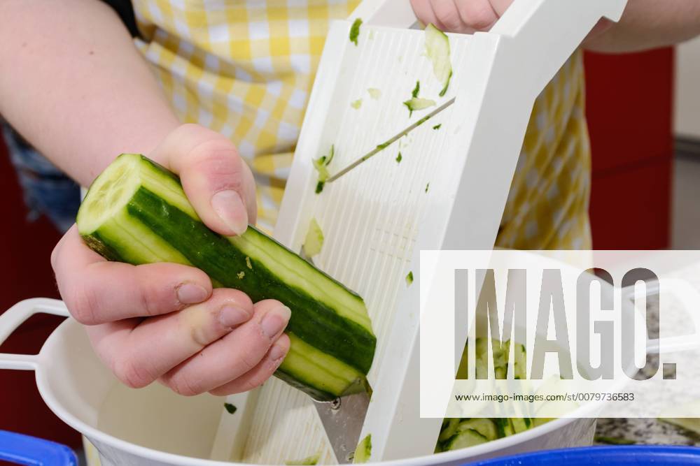 IMAGO Creative, Food, Gurkensalat Köchin schneidet frische Gurke mit Gurkenhobel für Salat 1077403659
