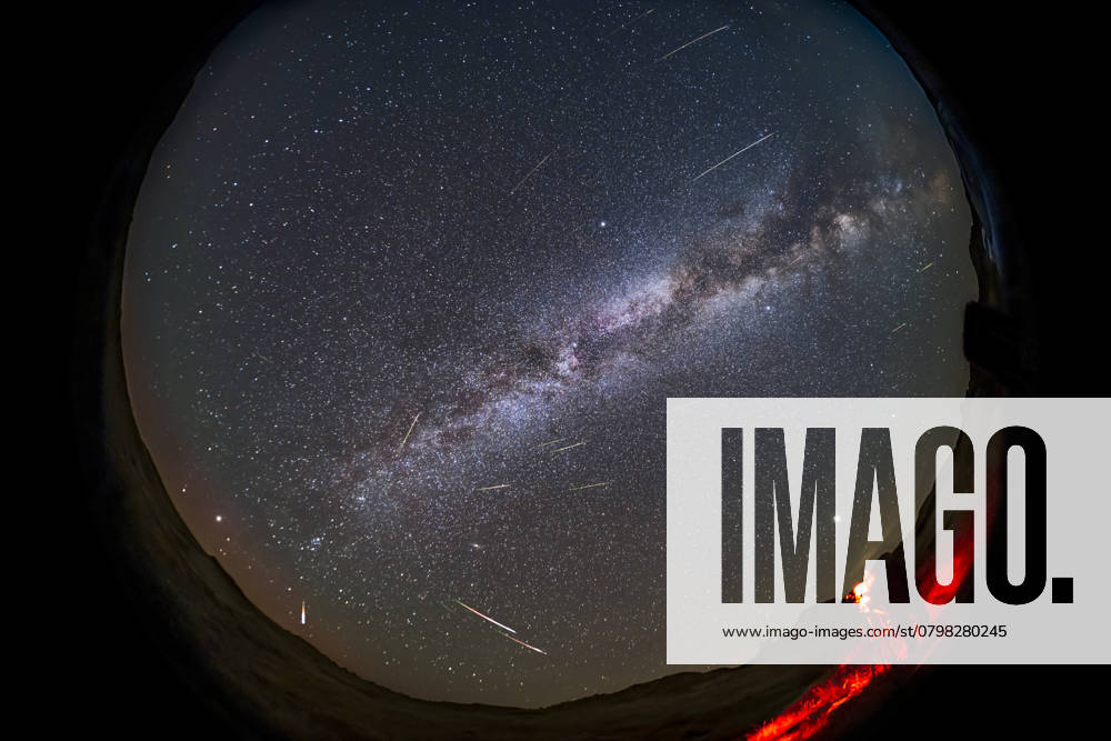 A selfie of astronomer setting up to photograph the 2021 Perseid meteor shower on August 12, 2021 at Dinosaur Provincial Park, Alberta, Canada, as one camera captures the scene looking east while I finish setting up another camera in the foreground. The radiant of the shower is obvious, in Perseus, at lower left in the northeast. The Milky Way stretches from northeast to southwest (top right). A dim red aurora is on the horizon to the northeast. Cygnus is overhead at centre. Jupiter is the bright object above me. The Big Dipper is at upper left low in the northwest. Model Released