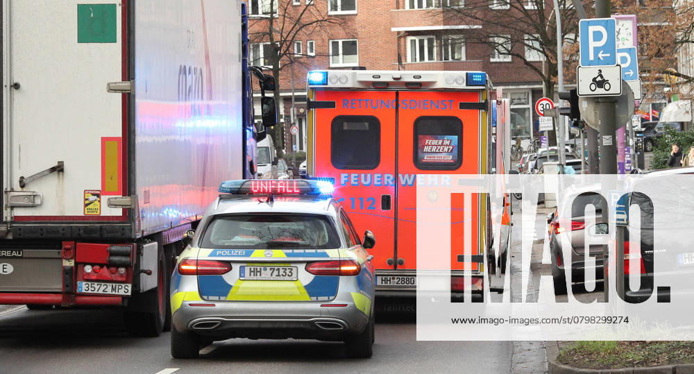 A police car with flashing blue lights and the words accident between the blue lights on a busy road In front of it is an ambulance from the Hamburg fire department with flashing blue lights Winterhude Hamburg