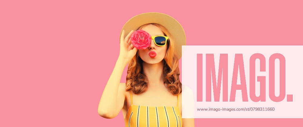 Sommer Porträt der stilvollen jungen Frau Modell bläst Kuss mit Blütenknospen auf rosa Hintergrund Summer portrait of stylish young woman model blowing kiss with flower buds looking for something in round straw hat on pink studio background ,model released, Symbolfoto