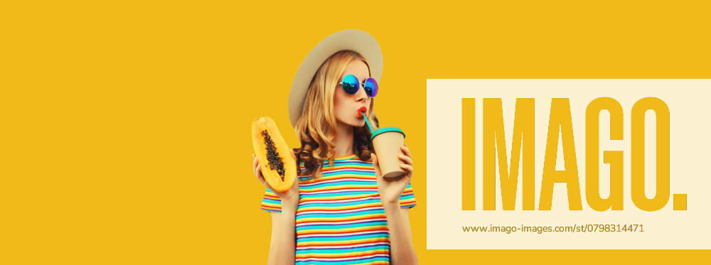 Sommer Porträt der stilvollen jungen Frau mit Papaya-Frucht trinken frischen Saft auf gelbem Hintergrund Summer portrait of stylish young woman with juicy papaya fruit drinking fresh juice looking away in straw hat, sunglasses on colorful yellow studio background