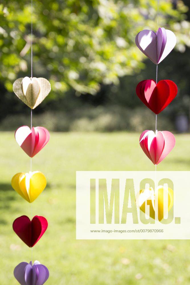 Heart-shaped garland made of paper hanging in garden CMF00691