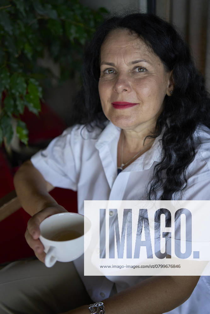 A 60s woman drinking nettle tea in modern coworking office during lunch break Model Released VictoriaAntre_ID25251_730488_047