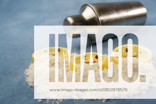Lemon slices with cloves and cinnamon forming a smiley face on a pile of salt next to a shaker with blue background with copy space 23592765 RECORD DATE NOT STATED